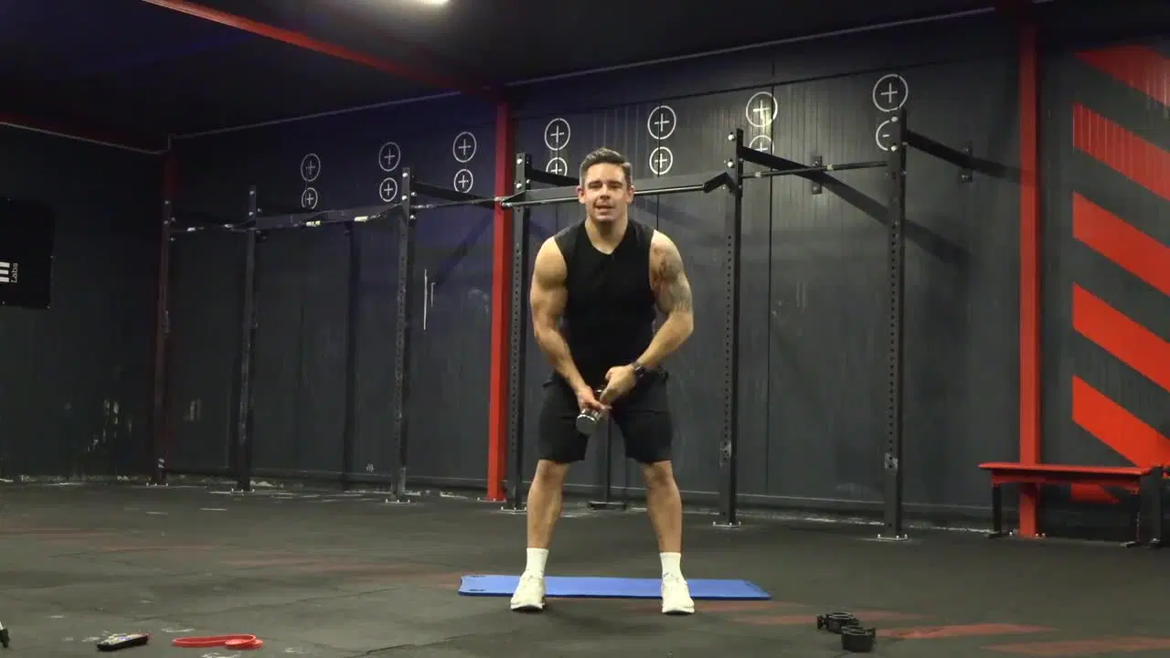Kadr z treningu CrossFit w domu - stabilizacja w ruchu z ciężarkami i gumą power band