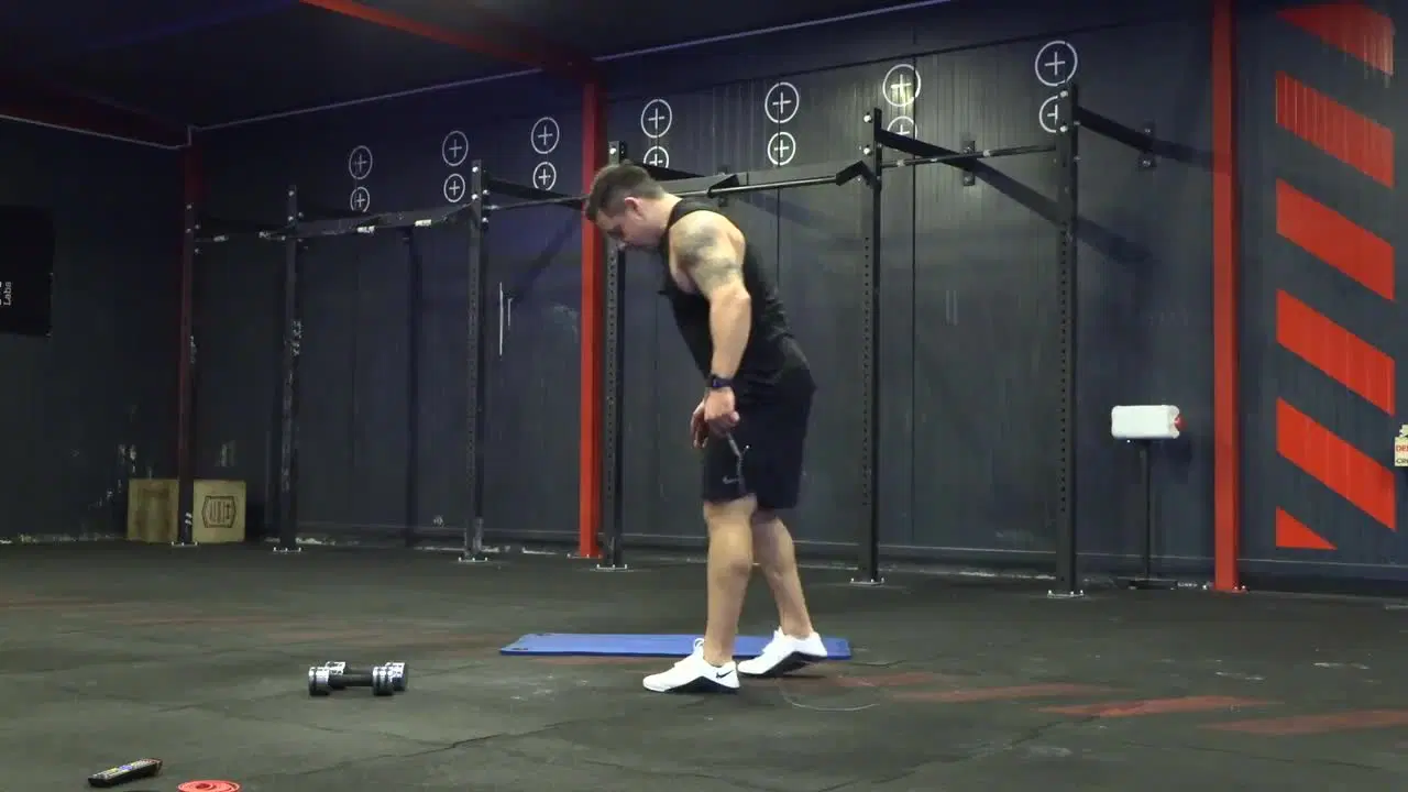 Kadr z treningu CrossFit w domu - stabilizacja w ruchu ze sprzętem