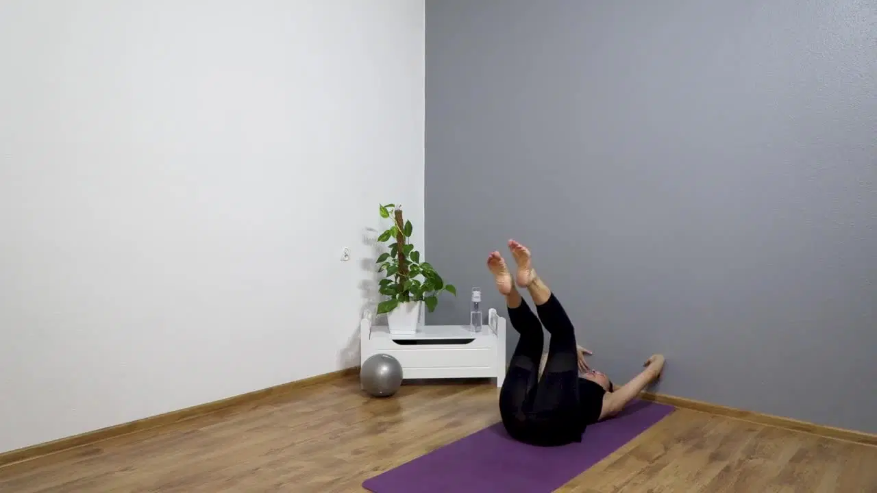 Kadr z treningu Pilates przy ścianie - smukłe ciało - stabilny core z piłką pilatesową