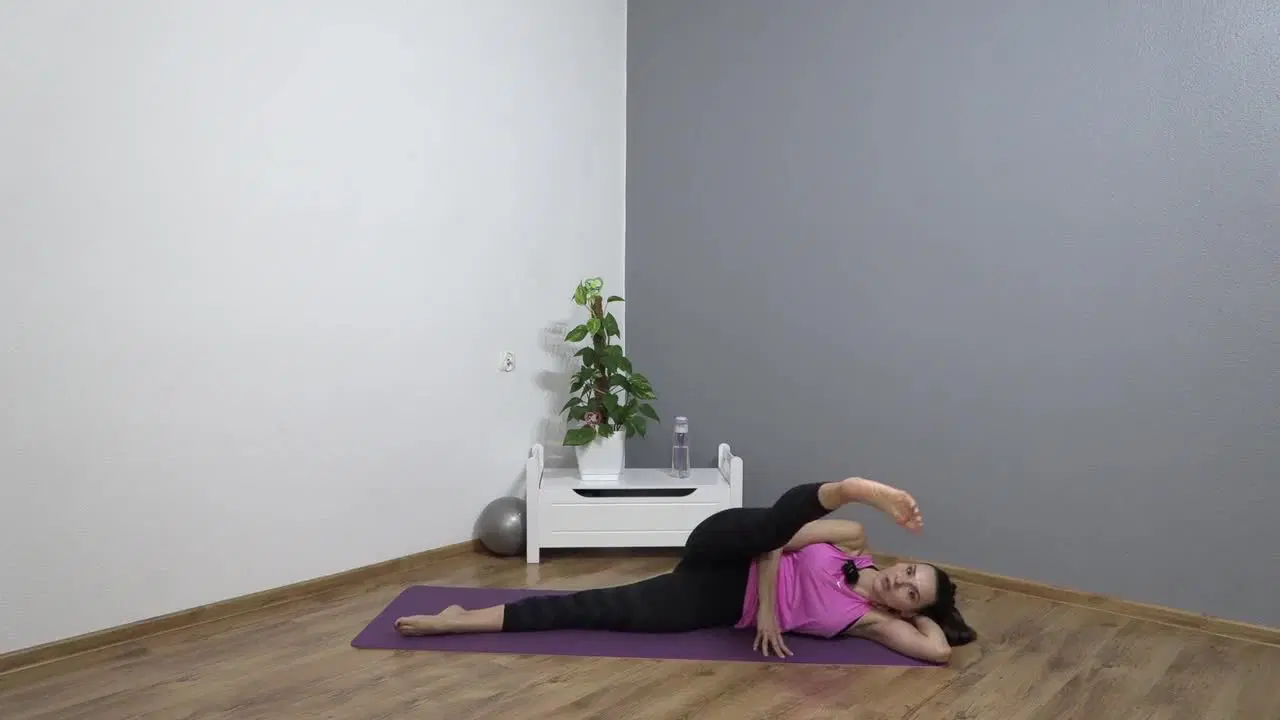 Kadr z treningu Pilates przy ścianie - smukłe ciało - mocny środek z taśmą pilatesową