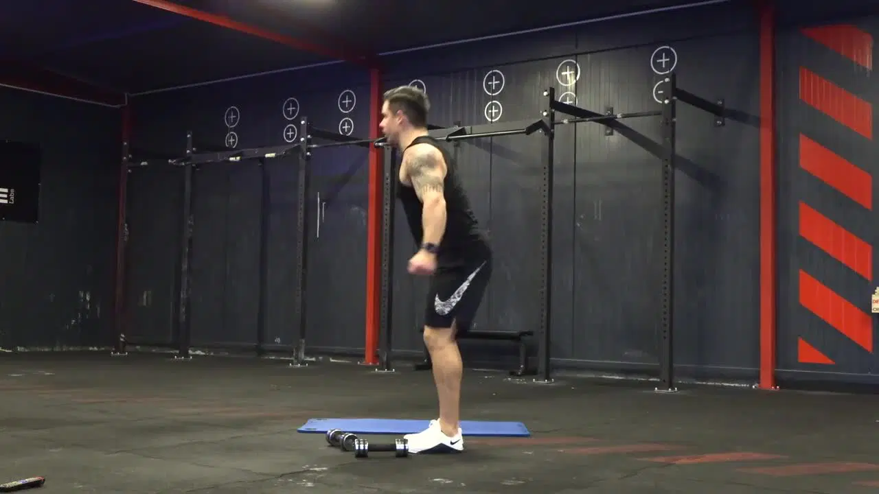 Kadr z treningu CrossFit w domu - stabilizacja w ruchu z ciężarkami