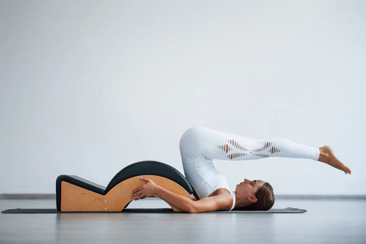 Kobieta wykonuje ćwiczenie Pilates na łuku do ćwiczeń.